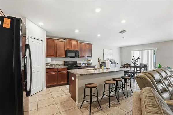 a kitchen with stainless steel appliances granite countertop a stove a refrigerator a sink a stove a dining table and chairs