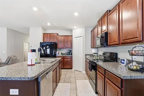 a kitchen with granite countertop stainless steel appliances a sink a stove top oven a counter space and cabinets