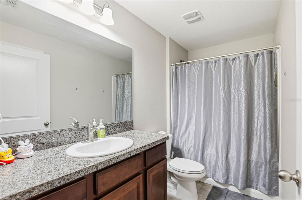 211 English Channel Place Dover, FL 33527 - Photo 8 of 35 a bathroom with a granite countertop sink a toilet and a mirror