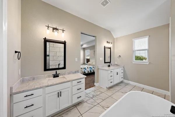 a spacious bathroom with a double vanity sink mirror and bathtub