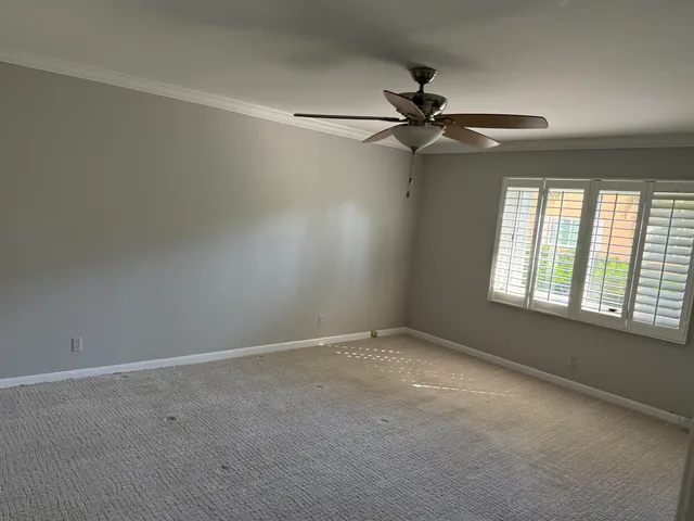 an empty room with a window and a fan