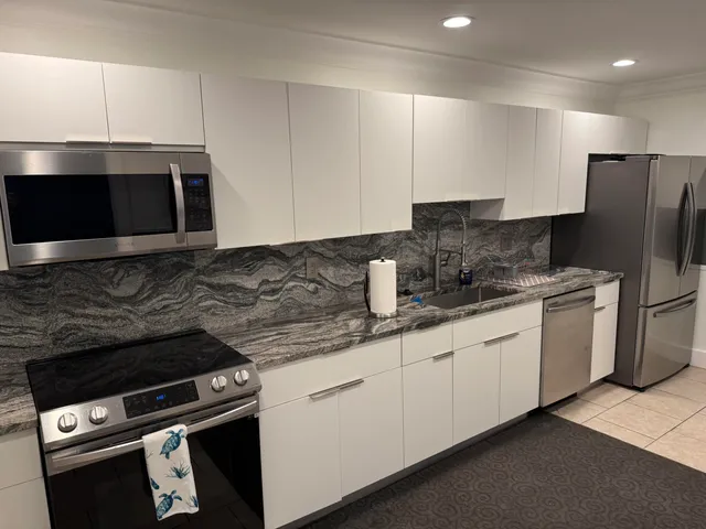 a kitchen with granite countertop a sink a stove a refrigerator and cabinets