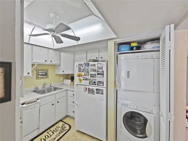 a kitchen with a refrigerator a sink and dishwasher with white cabinets