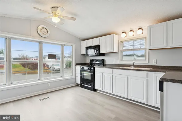 a kitchen with granite countertop a stove a sink and a refrigerator