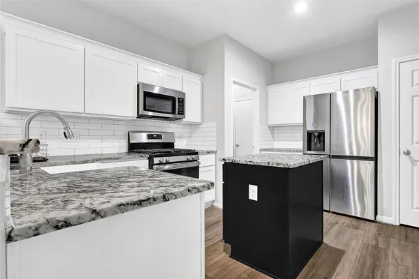 a kitchen with granite countertop a refrigerator stove and sink