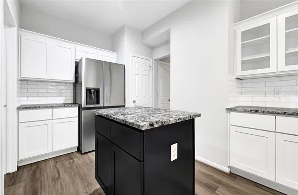 a kitchen with kitchen island granite countertop white cabinets and refrigerator