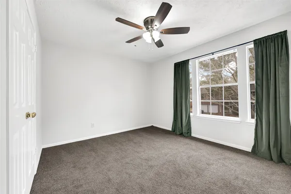 an empty room with ceiling fan and windows