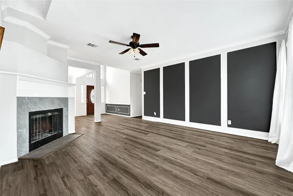 a view of an empty room with wooden floor fireplace and a window