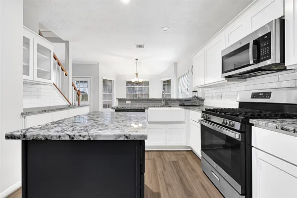a kitchen with stainless steel appliances kitchen island granite countertop a sink stove and microwave