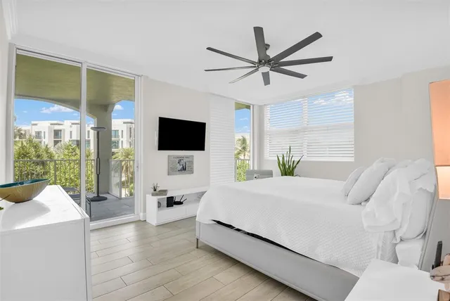 a bedroom with a bed a flat screen tv and a large window