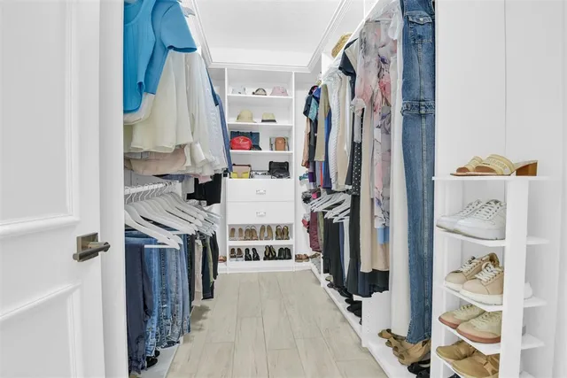 a view of walk in closet with clothes and shoes
