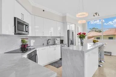 a kitchen with stainless steel appliances granite countertop a stove a sink dishwasher and white cabinets with wooden floor