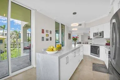 a large white kitchen with stainless steel appliances granite countertop a lot of counter top space and wooden floor