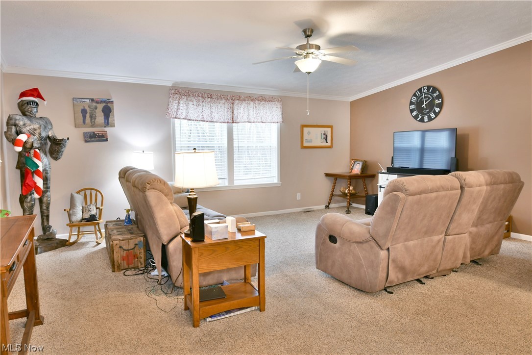 1570 Kale Adams Road Southwest Warren, OH 44481 - Photo 23 of 34 Living room with ceiling fan, light colored carpet, and crown molding
