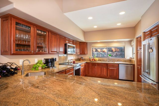 a large kitchen with granite countertop a large counter top stainless steel appliances and cabinets