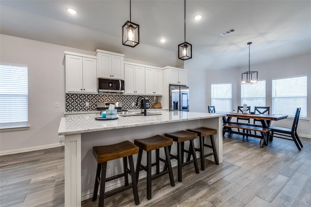 8730 Dunlap Street Dallas, TX 75217 - Photo 5 of 15 a kitchen with stainless steel appliances granite countertop a stove a refrigerator a sink a dining table and chairs with wooden floor