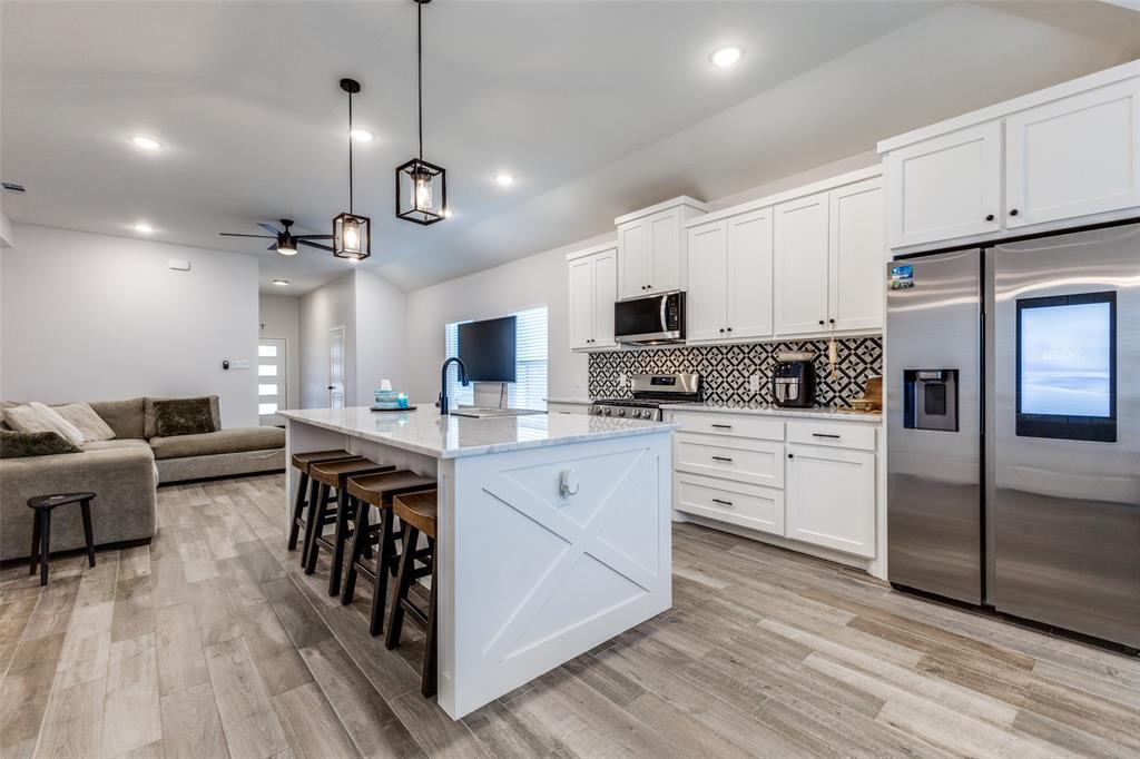 8730 Dunlap Street Dallas, TX 75217 - Photo 6 of 15 a kitchen with stainless steel appliances kitchen island granite countertop a stove a sink dishwasher a refrigerator and white cabinets with wooden floor