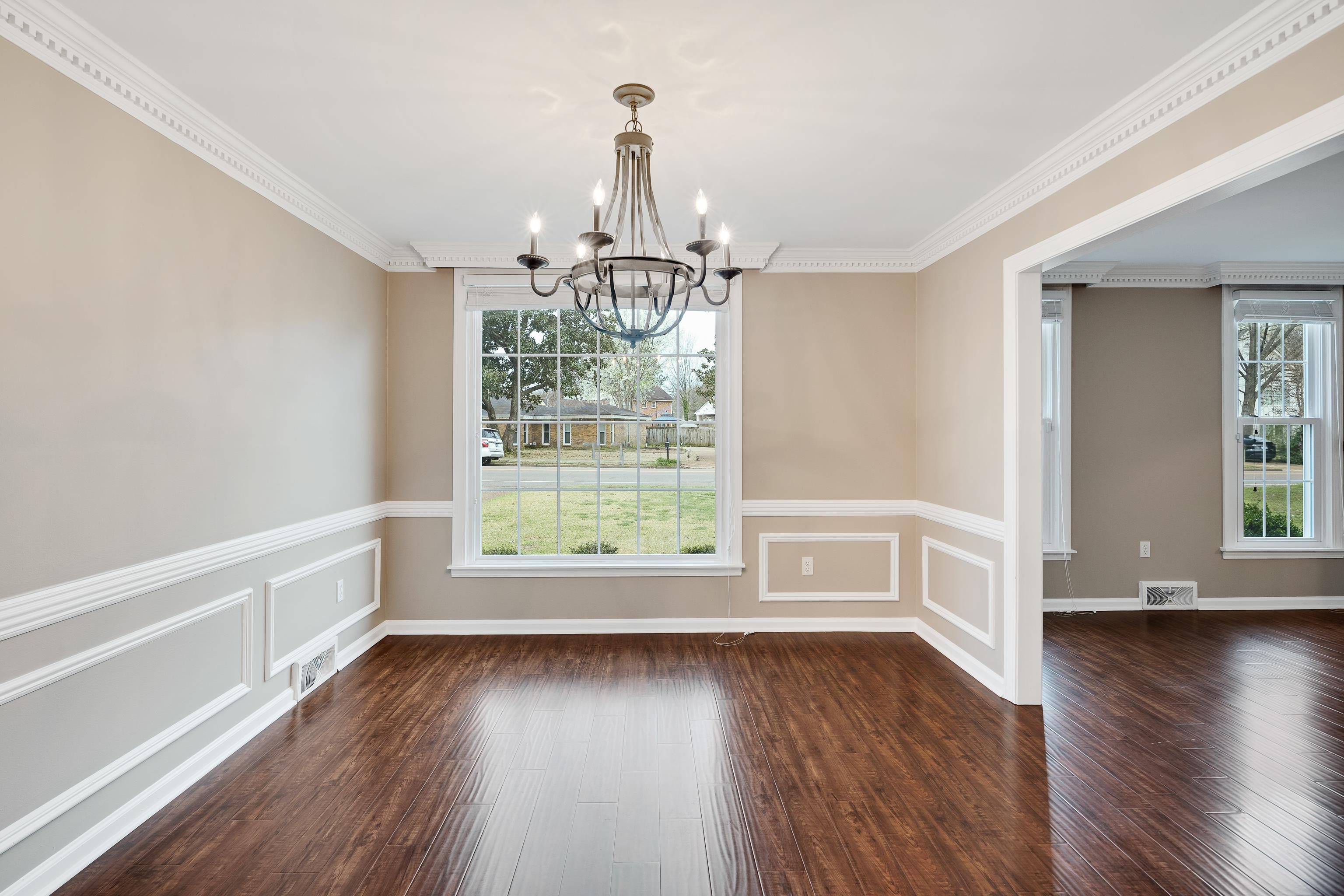 1658 Miller Farms Road Germantown, TN 38138 - Photo 7 of 39 Unfurnished dining area with a chandelier, ornamental molding, dark wood-style flooring, a decorative wall, and a wainscoted wall