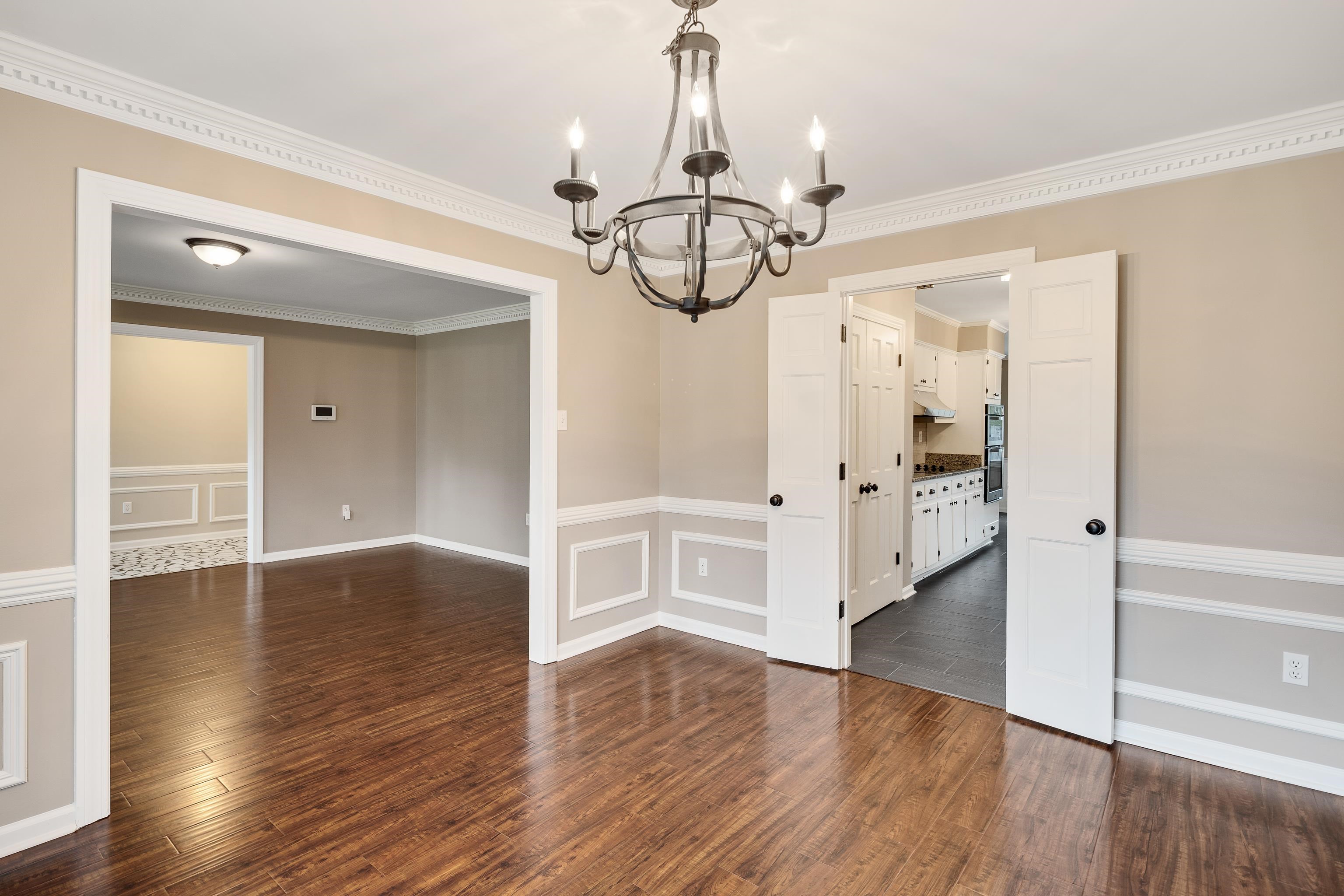 1658 Miller Farms Road Germantown, TN 38138 - Photo 8 of 39 Unfurnished dining area featuring dark wood-style flooring, a decorative wall, ornamental molding, hanging lights, and wainscoting