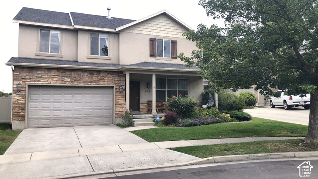Two-story stucco exterior with stone veneer accents, an attached two-car garage, and a covered front porch