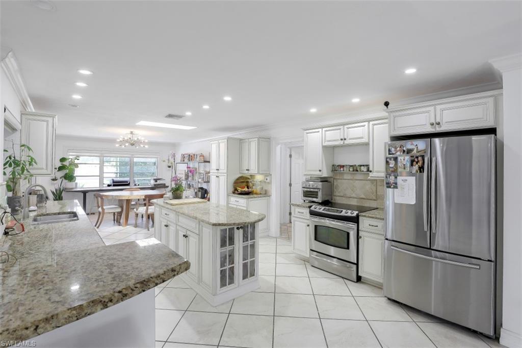 619 Neapolitan Way Naples, FL 34103 - Photo 8 of 32 a kitchen with stainless steel appliances granite countertop a refrigerator and a stove top oven