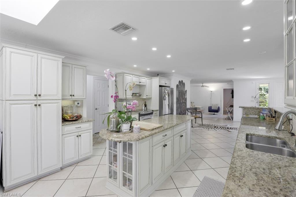 619 Neapolitan Way Naples, FL 34103 - Photo 9 of 32 a kitchen with white cabinets and dining table