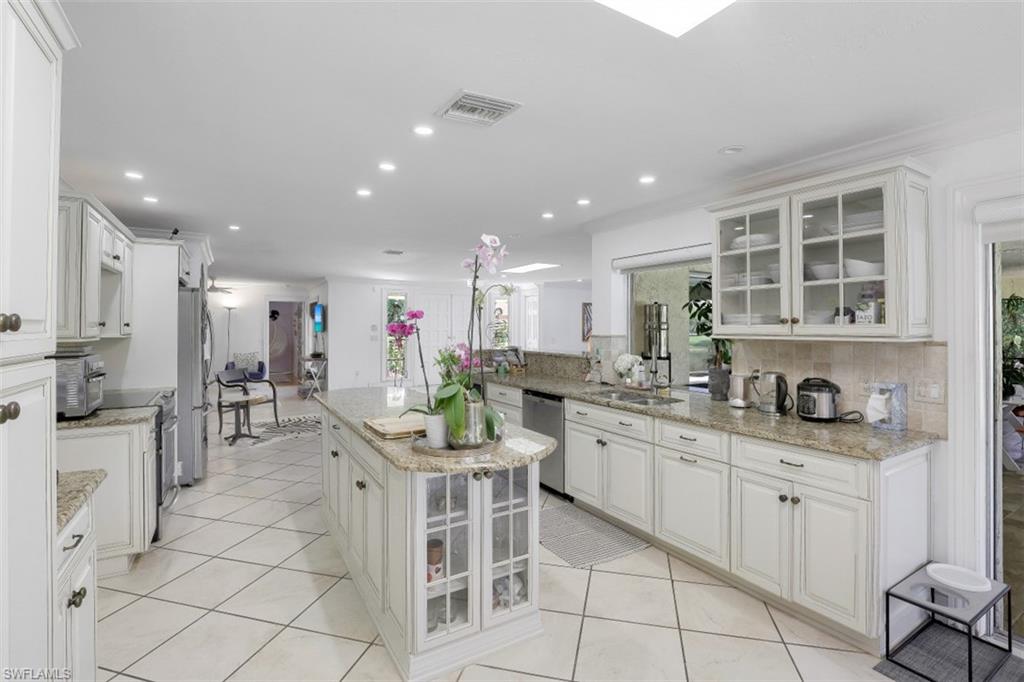 619 Neapolitan Way Naples, FL 34103 - Photo 10 of 32 a kitchen with a sink and chairs