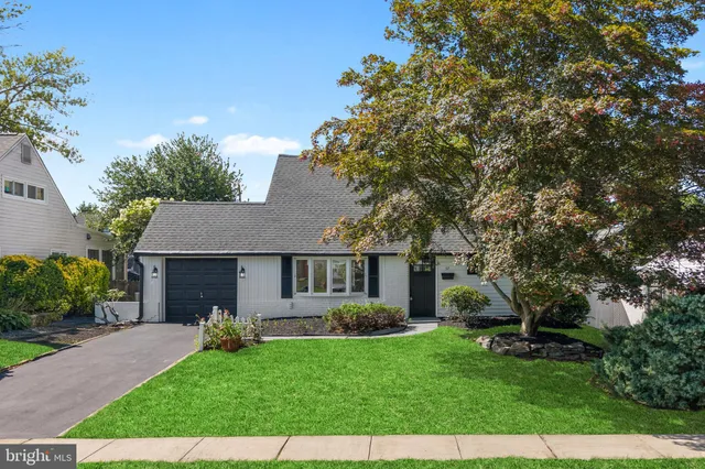 a front view of a house with a yard and trees