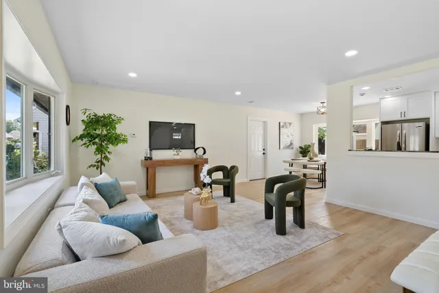 a living room with furniture kitchen view and a wooden floor