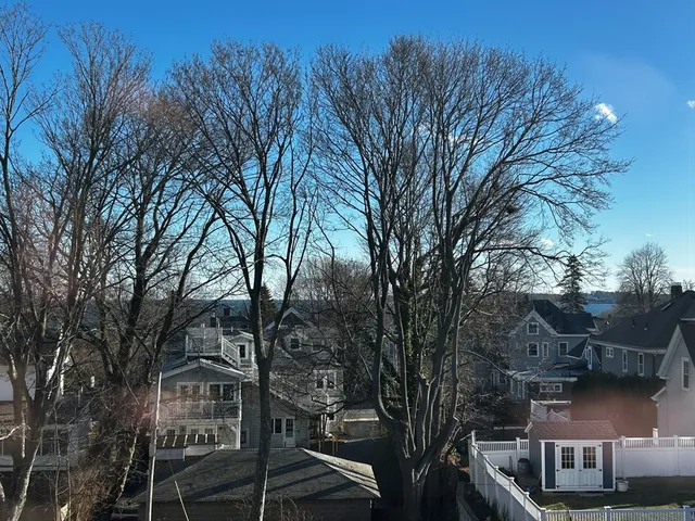 a view of an empty room with window and kitchen view