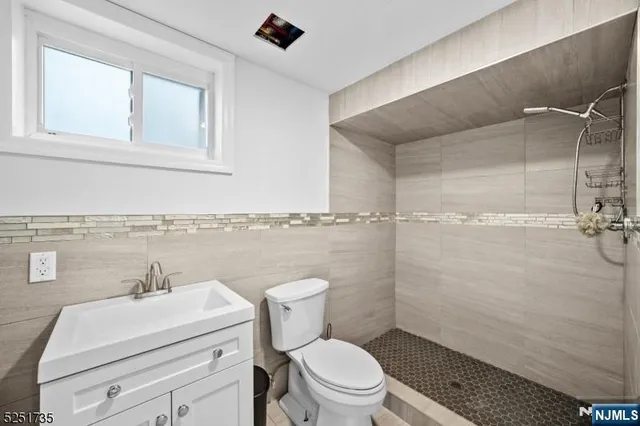 a bathroom with a granite countertop toilet a sink a mirror and shower