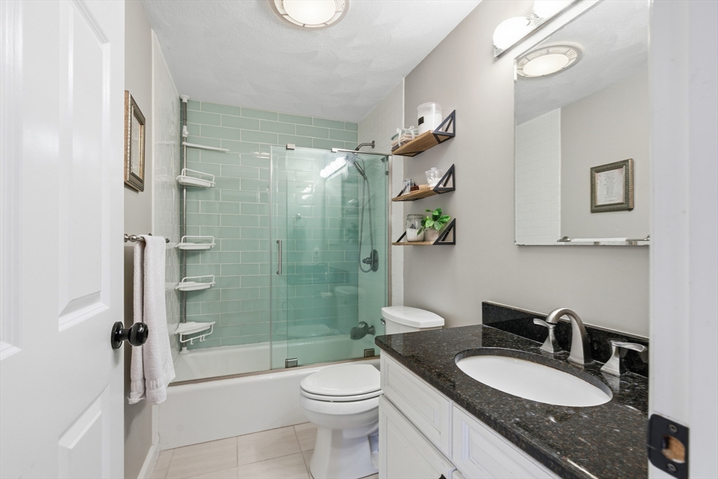27 Emerson Street, Unit 27 Stoneham, MA 02180 - Photo 14 of 29 a bathroom with a granite countertop sink a toilet a mirror and shower
