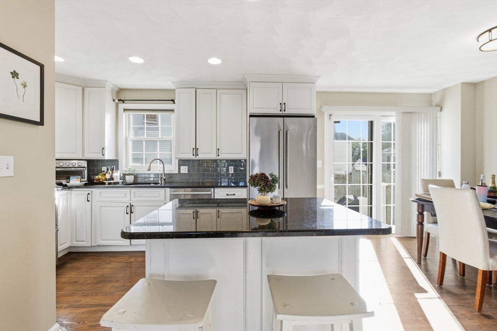 27 Emerson Street, Unit 27 Stoneham, MA 02180 - Photo 8 of 29 a kitchen with stainless steel appliances granite countertop a refrigerator a stove and white cabinets with wooden floor