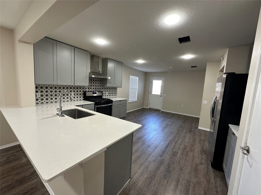 3416 Autumn Bay Drive Austin, TX 78744 - Photo 2 of 14 a kitchen with a sink a refrigerator a stove and a wooden floor