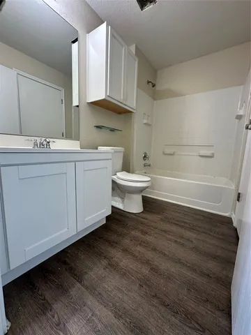 an empty room with wooden floor chandelier fan and windows
