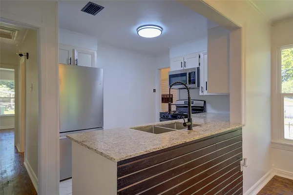 a room with kitchen island a sink stainless steel appliances and cabinets
