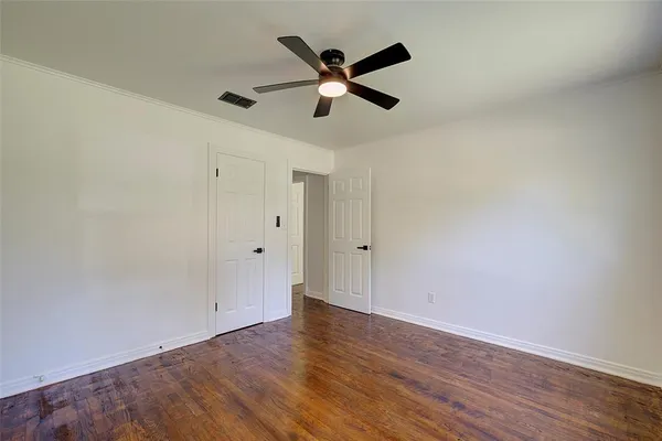 an empty room with wooden floor and ceiling fan