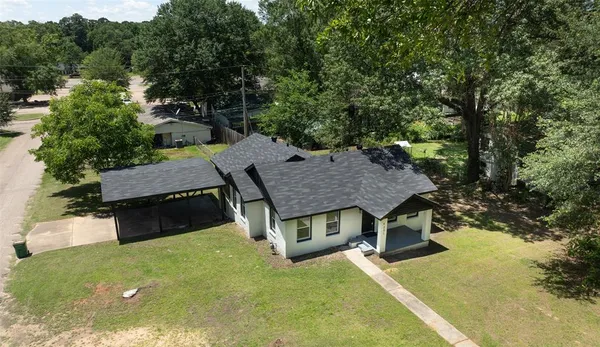 an aerial view of a house with swimming pool and large trees