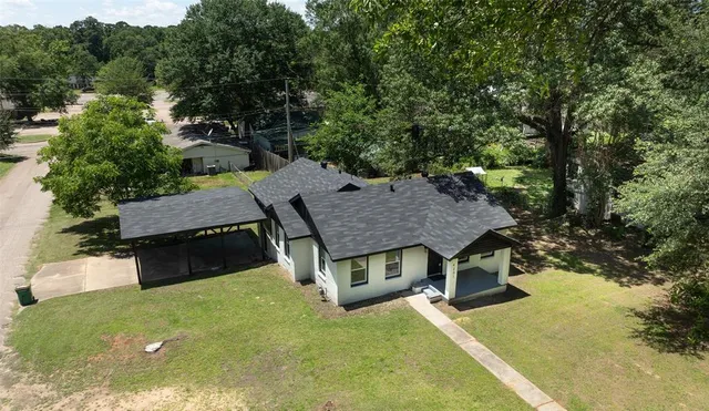 an aerial view of a house with swimming pool and large trees