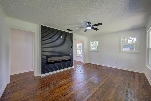 a view of an empty room with wooden floor fireplace and a window