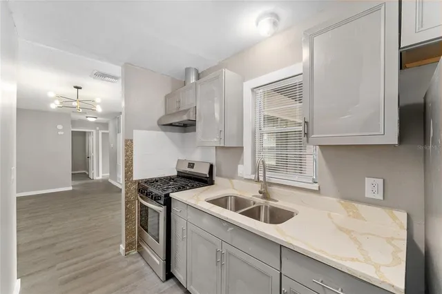 a kitchen that has a sink a stove and cabinets