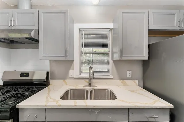 a kitchen with stainless steel appliances granite countertop a sink a stove and white cabinets