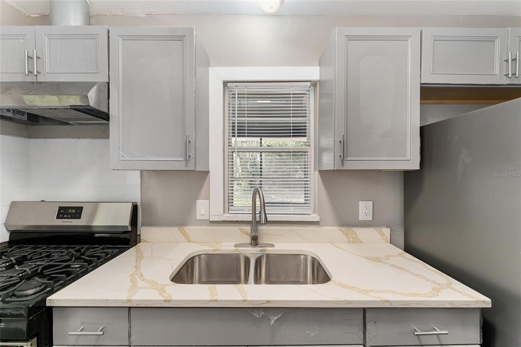 919 Southeast 19th Street Gainesville, FL 32641 - Photo 19 of 50 a kitchen with stainless steel appliances granite countertop a sink a stove and white cabinets