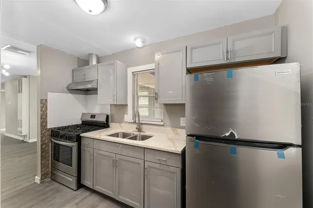 a kitchen with stainless steel appliances a refrigerator a sink and white cabinets