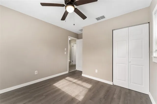 an empty room with wooden floor closet and ceiling fan