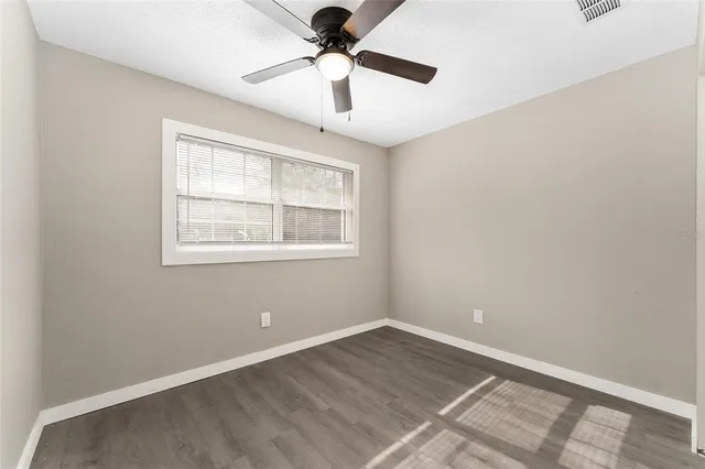 a view of an empty room with a window and wooden floor