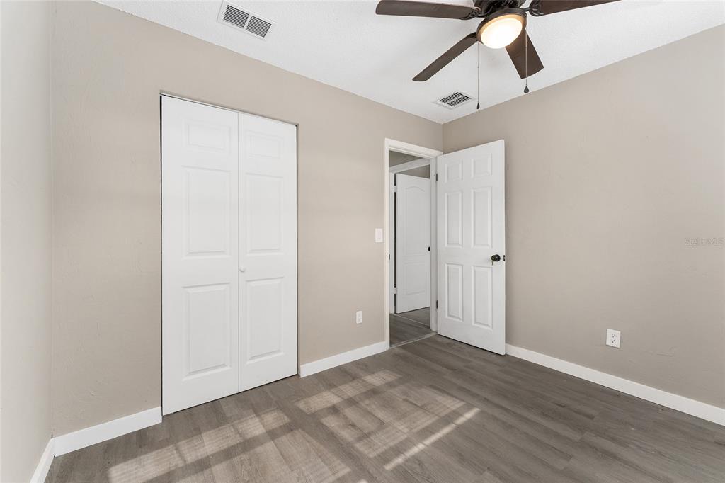 919 Southeast 19th Street Gainesville, FL 32641 - Photo 27 of 50 an empty room with wooden floor ceiling fan and windows