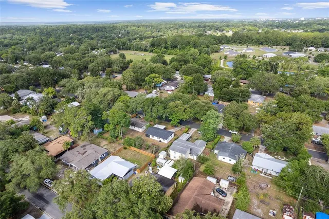 an aerial view of residential houses with outdoor space and trees