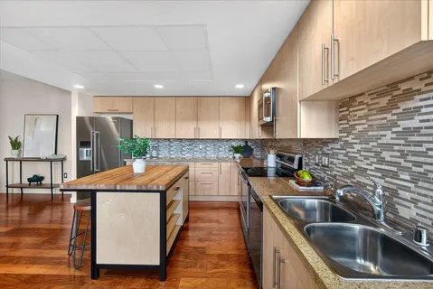 a kitchen with stainless steel appliances granite countertop a sink a stove and a wooden floors