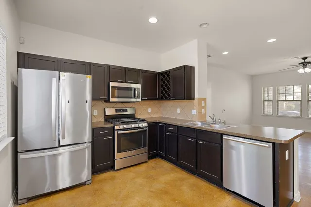 a kitchen with stainless steel appliances granite countertop a refrigerator a sink a stove a microwave and a refrigerator